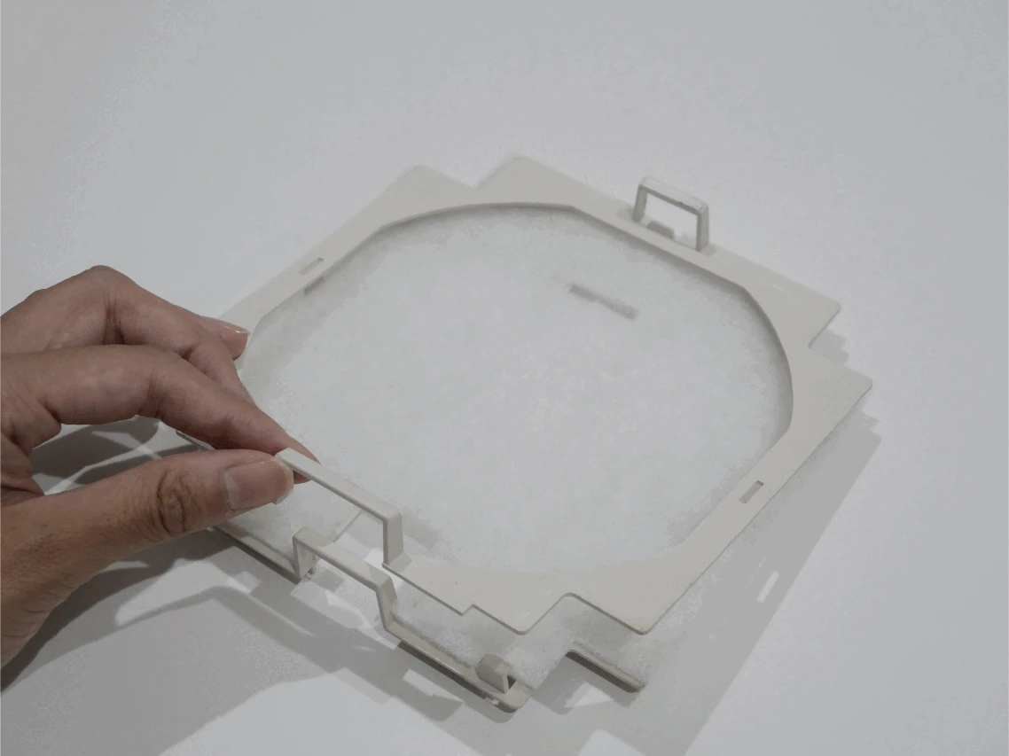 フィルターケースへの装着工程1。既存のフィルターケースの凸部を持って開き、上下3か所のツメがある部品を確認します。